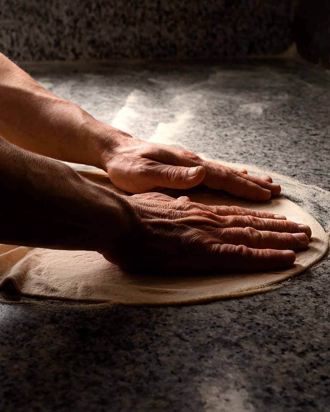 Fotografia d'un treballador amassant la massa de la pizza.